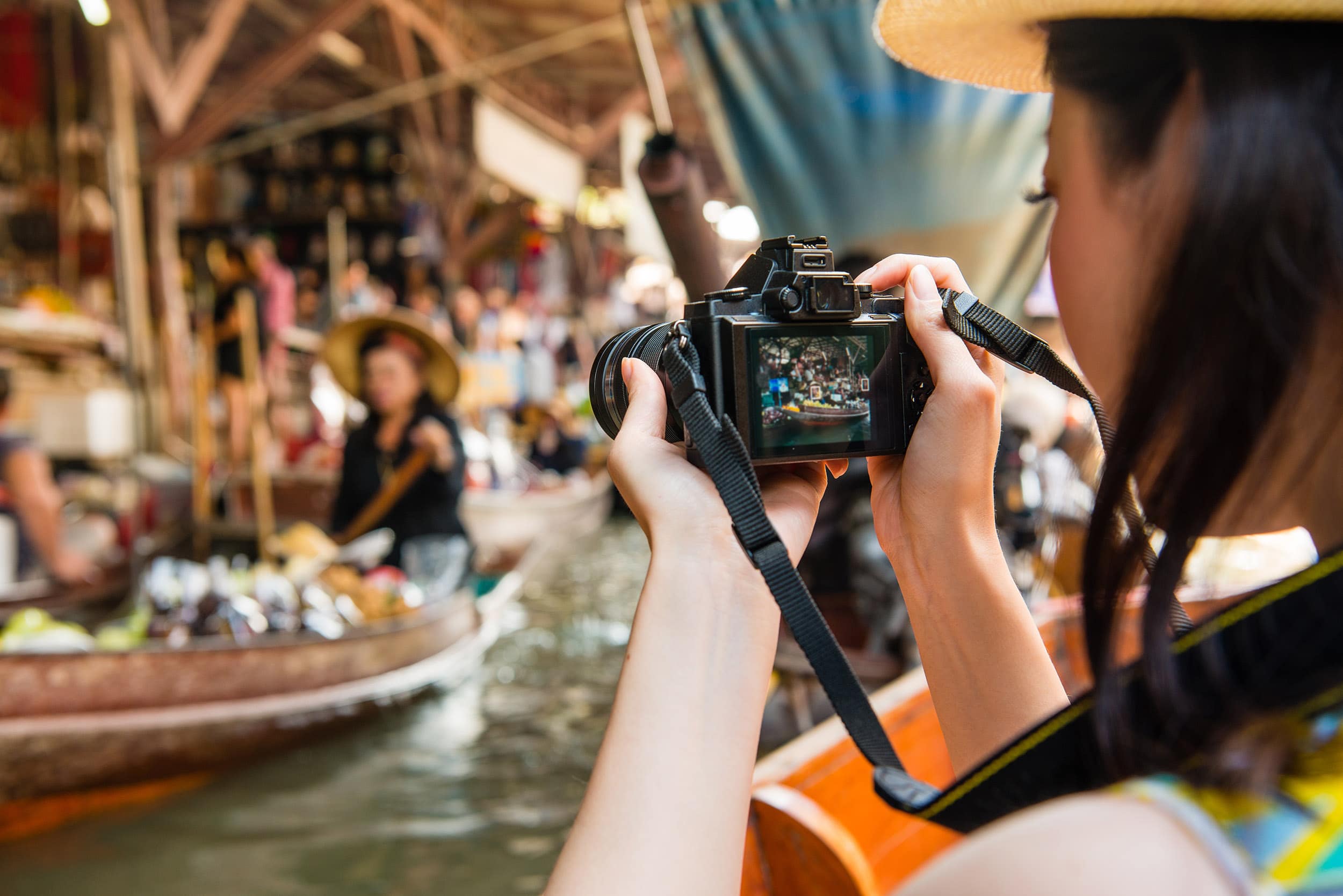 Girl photographing lady in damnoen saduak floating market
